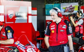 Gigi Dall'Igna, con cascos de radio, observa una Ducati en el box del equipo oficial durante un Gran Premio de MotoGP