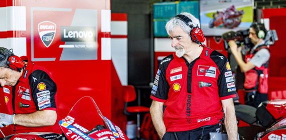 Gigi Dall'Igna, con cascos de radio, observa una Ducati en el box del equipo oficial durante un Gran Premio de MotoGP