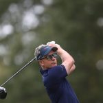 Luke Donald, con visera y gafas de sol, sigue la trayectoria de su golpe con el driver tras la salida en un tee arbolado