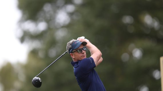 Luke Donald, con visera y gafas de sol, sigue la trayectoria de su golpe con el driver tras la salida en un tee arbolado