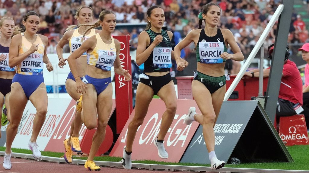 Marta García, con top verde y negro, encabeza a un grupo de corredoras en la recta de la pista, con la grada llena al fondo
