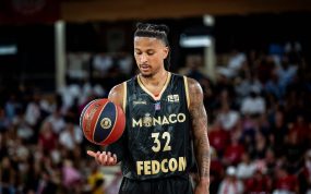 Matthew Strazel, con la camiseta negra y dorada del Mónaco, deja el balón suspendido sobre la palma de la mano en un pabellón