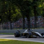 Un monoplaza pasa a toda velocidad junto a una grada llena en un circuito rodeado de árboles