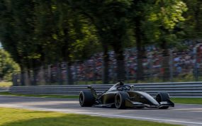 Un monoplaza pasa a toda velocidad junto a una grada llena en un circuito rodeado de árboles