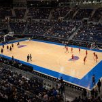 Vista elevada de una pista de baloncesto en un pabellón cubierto durante el calentamiento previo a un partido internacional