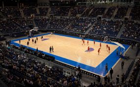 Vista elevada de una pista de baloncesto en un pabellón cubierto durante el calentamiento previo a un partido internacional