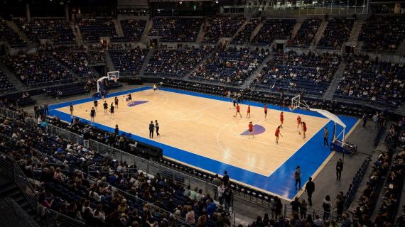 Vista elevada de una pista de baloncesto en un pabellón cubierto durante el calentamiento previo a un partido internacional