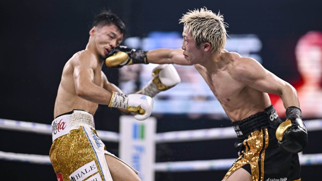 Naoya Inoue, con calzón negro y dorado, lanza un golpe a la cara de Junto Nakatani sobre el ring