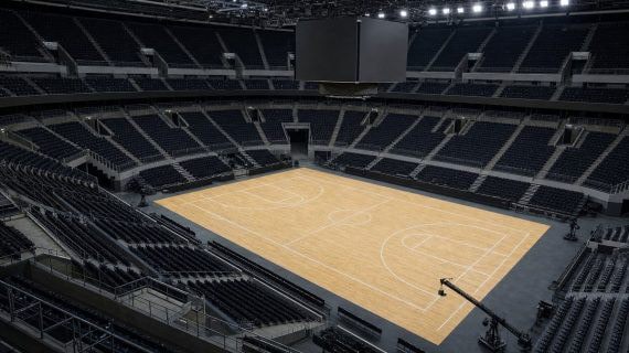 Pista de baloncesto vacía de un pabellón moderno vista desde la esquina alta del graderío
