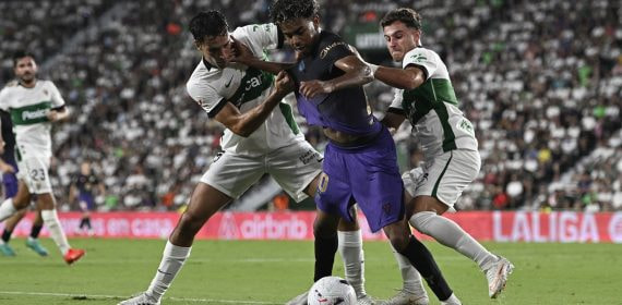 Federico Redondo y Germán Valera disputan un balón a Lamine Yamal durante un Elche - FC Barcelona de LaLiga 2026/27.