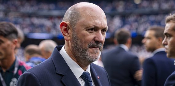 Rafael Louzán, presidente de la RFEF, con traje azul marino sobre el césped de un estadio con las gradas llenas