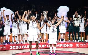 Los jugadores del Real Madrid, con camiseta blanca, levantan los brazos alrededor del trofeo en el podio de campeones de la SuperCup