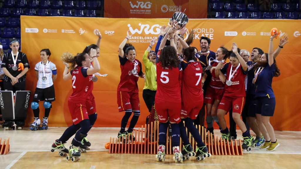Las jugadoras de la selección española de hockey patines, con camiseta roja, levantan el trofeo de campeonas del mundo sobre la pista