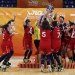Las jugadoras de la selección española de hockey patines, con camiseta roja, levantan el trofeo de campeonas del mundo sobre la pista