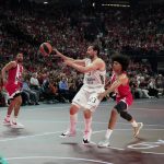 Sergio Llull se eleva para dar un pase entre dos defensores del Olympiacos