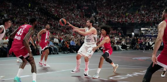 Sergio Llull se eleva para dar un pase entre dos defensores del Olympiacos