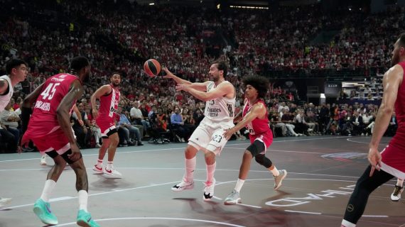 Sergio Llull se eleva para dar un pase entre dos defensores del Olympiacos