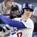 Un bateador de los Dodgers con casco azul y el dorsal 17 sigue con la mirada la bola tras golpearla, con el público detrás
