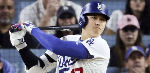 Un bateador de los Dodgers con casco azul y el dorsal 17 sigue con la mirada la bola tras golpearla, con el público detrás