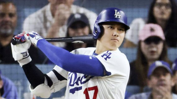 Un bateador de los Dodgers con casco azul y el dorsal 17 sigue con la mirada la bola tras golpearla, con el público detrás