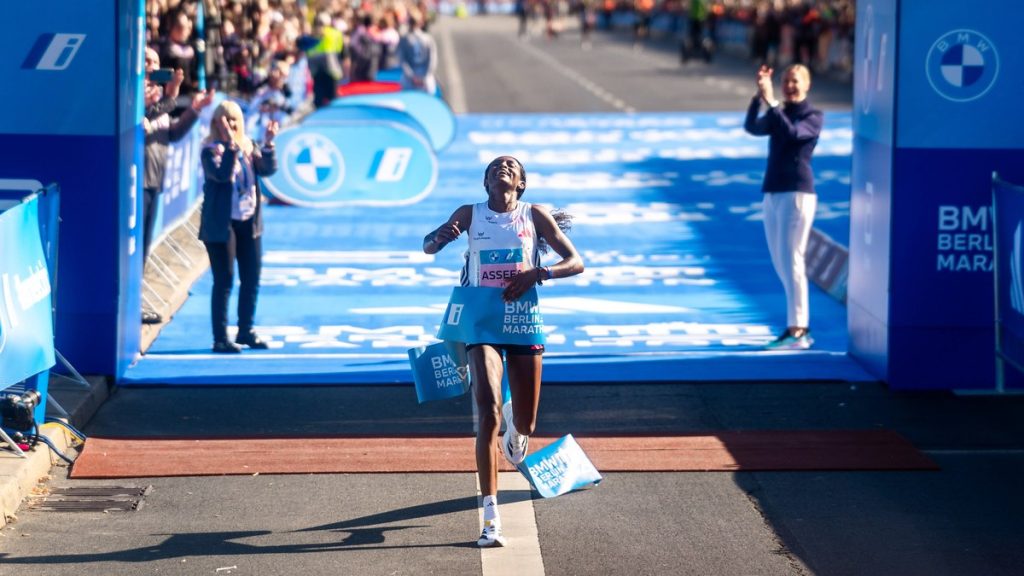 Tigst Assefa, con los brazos abiertos y la mirada al cielo, rompe la cinta de meta sobre la alfombra azul del maratón