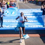 Tigst Assefa, con los brazos abiertos y la mirada al cielo, rompe la cinta de meta sobre la alfombra azul del maratón