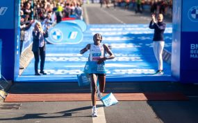 Tigst Assefa, con los brazos abiertos y la mirada al cielo, rompe la cinta de meta sobre la alfombra azul del maratón