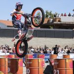 Toni Bou, con casco y mono de Repsol, salta con su moto de trial sobre una fila de barriles naranjas ante el público