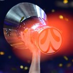 Una mano levanta el trofeo de campeón de la Euroliga entre confeti dorado y los focos de un pabellón a oscuras