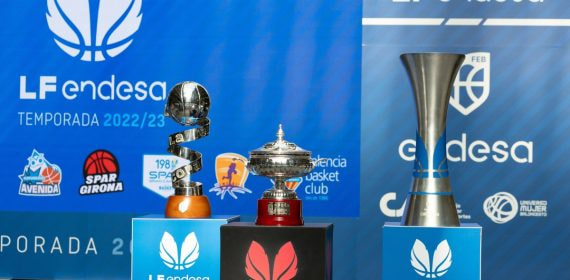 Los trofeos de la Copa de la Reina, la Supercopa y la Liga Femenina Endesa sobre tres pedestales ante un fondo azul