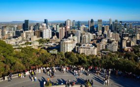 Visitantes en el mirador del Mont Royal con los rascacielos del centro de Montreal y el río San Lorenzo al fondo