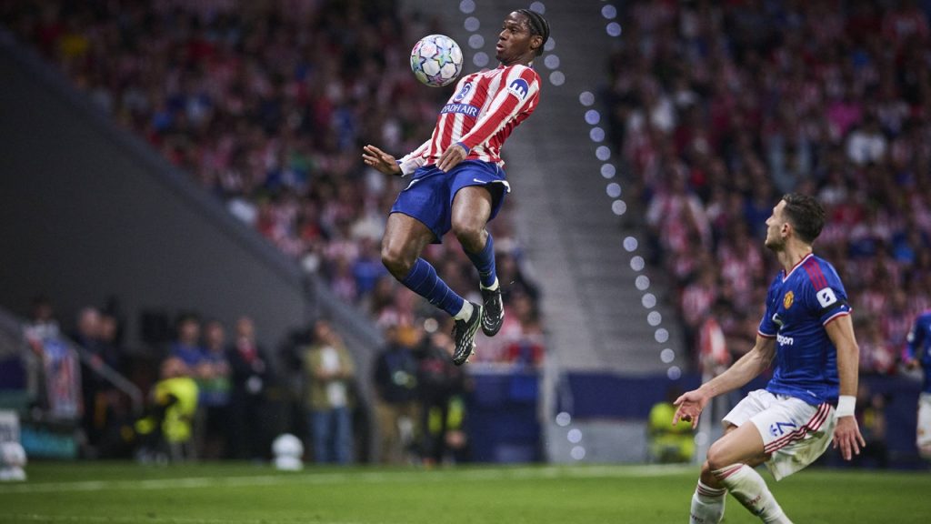 Jonathan David gana un balón aéreo ante la mirada de Diogo Dalot en el partido entre el Atlético de Madrid y el Manchester United de la fase liga de la Champions 2026/27.
