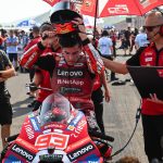 Marc Márquez se quita el casco, sentado en su moto en la parrilla de salida, junto a dos miembros del equipo Ducati durante el Gran Premio de Indonesia de MotoGP.