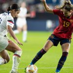 Olga Carmona, de rojo, protege el balón ante Sophia Smith, de blanco, sobre el césped