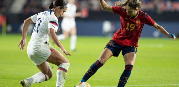 Olga Carmona, de rojo, protege el balón ante Sophia Smith, de blanco, sobre el césped