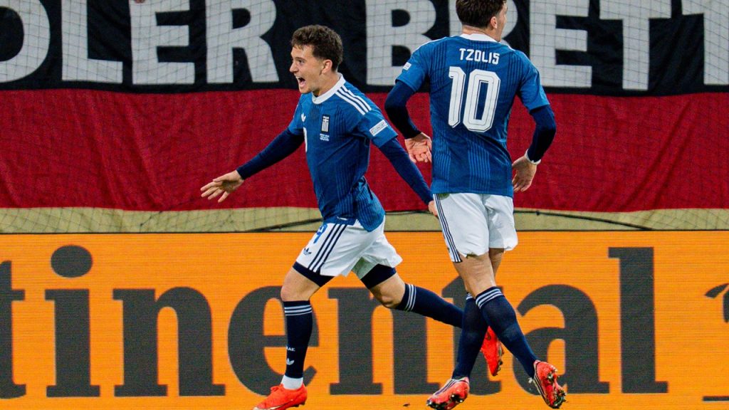 Konstantinos Karetsas celebra, junto a Christos Tzolis, el gol anotado por Dimitris Kourbelis en la victoria de Grecia frente a Alemania en Augsburgo, en un partido correspondiente a la Nations League 2026/27.