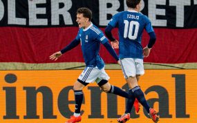 Konstantinos Karetsas celebra, junto a Christos Tzolis, el gol anotado por Dimitris Kourbelis en la victoria de Grecia frente a Alemania en Augsburgo, en un partido correspondiente a la Nations League 2026/27.