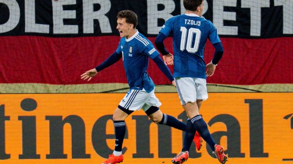 Konstantinos Karetsas celebra, junto a Christos Tzolis, el gol anotado por Dimitris Kourbelis en la victoria de Grecia frente a Alemania en Augsburgo, en un partido correspondiente a la Nations League 2026/27.