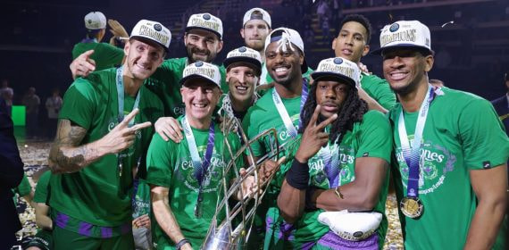 Los jugadores del Unicaja, con gorras de campeones y medallas, celebran junto al trofeo