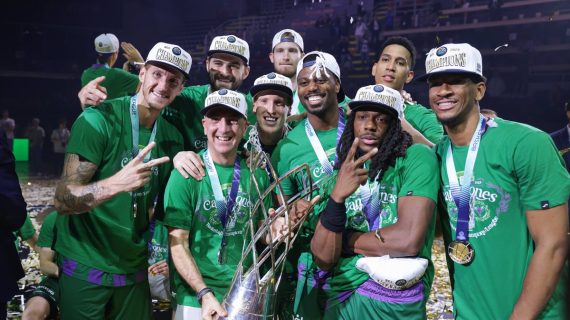 Los jugadores del Unicaja, con gorras de campeones y medallas, celebran junto al trofeo